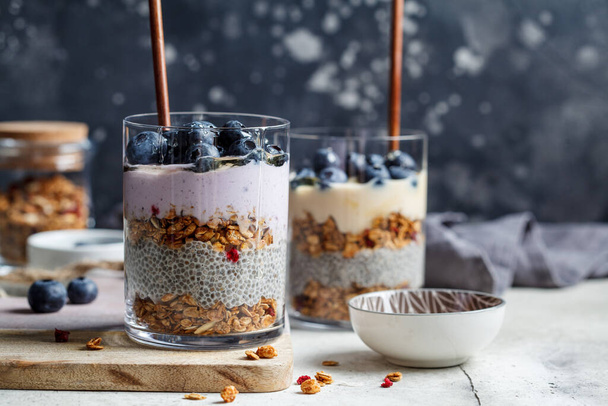 Breakfast parfait with chia, granola, berries and yogurt in a glass. Layer dessert in a glass. - Foto, afbeelding