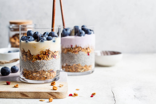 Breakfast parfait with chia, granola, berries and yogurt in a glass. Layer dessert in a glass. - Foto, immagini