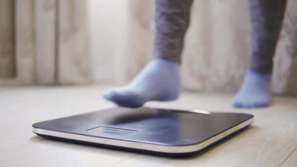 Woman feet step on weighing scales. Female checking body weight in room. - Footage, Video