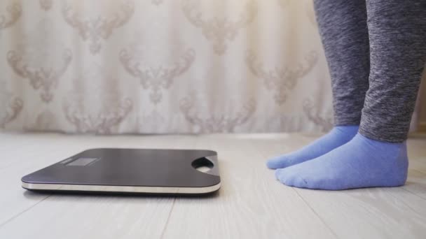 Mulher em meias e leggings verifica o peso do peso eletrônico usando display
 - Filmagem, Vídeo