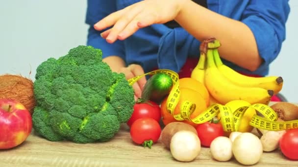 Młoda kobieta na ścisłej diecie na tle świeżych warzyw i owoców - Materiał filmowy, wideo