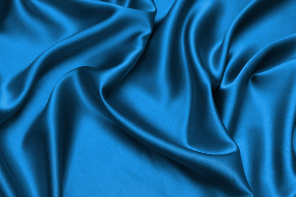 Niebieska satyna, jedwabista tkanina, fala, draperia. Piękne tło tekstylne. - Zdjęcie, obraz
