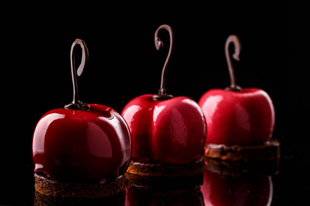 Glossy mousse cakes in the form of cherries on a black background - Foto, imagen