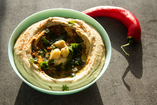 Πιάτο φρέσκο σπιτικό χούμους με πίτα στο τραπέζι. Αυθεντικό φαγητό της Μέσης Ανατολής. Υγιεινή διατροφική έννοια. Χορτοφαγικό ισορροπημένο πιάτο. Παραδοσιακό γεύμα του Ισραήλ.   - Φωτογραφία, εικόνα
