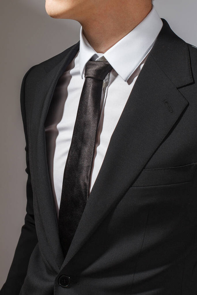 A man in a black suit and a white shirt with a black tie - 写真・画像
