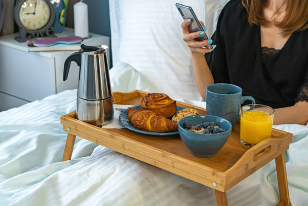 Happy young beautiful woman awaiting breakfast in bed in her bedroom. Good morning concept - Fotografie, Obrázek