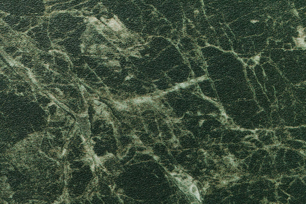Texture of dark green marble for tabletop with olive lines of a pattern, macro background. Artificial stone countertop from mineral tile for covering table on kitchen, backdrop closeup. - Photo, Image