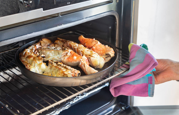 Para remover a lagosta grelhada do forno com uma toalha de prato
 - Foto, Imagem