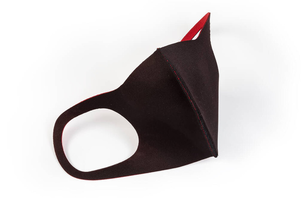 Máscara protectora elástica de tela negra con interior rojo sobre fondo claro
 - Foto, imagen