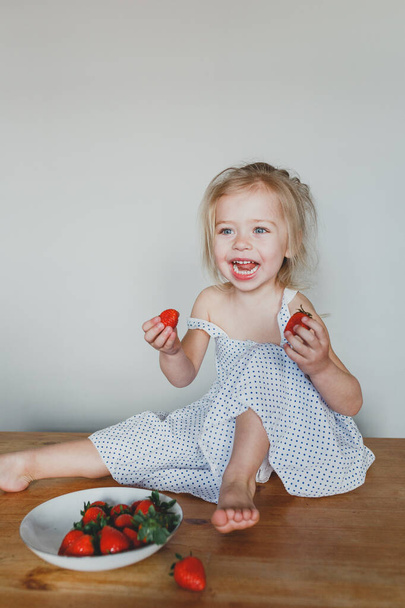 cute European girl eating strawberries. a beautiful, cheerful bl - Foto, Imagen