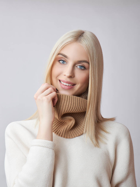 Blonde woman with long hair in a white sweater. Beauty portrait of a girl, natural cosmetics - Photo, Image