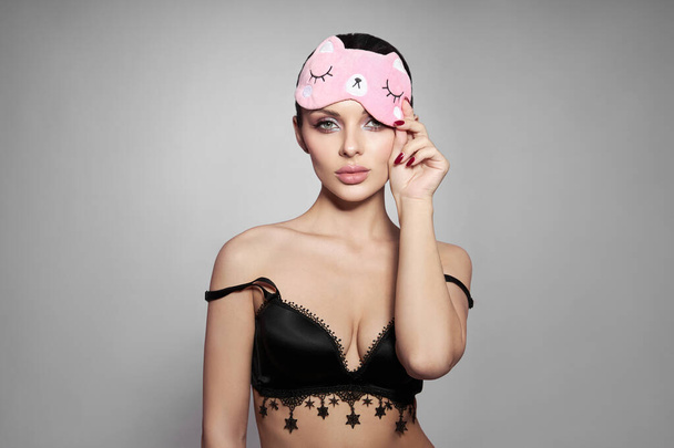 Beauty portrait of a Woman with a sleep mask and pink delicate makeup on her lips and eyes. Sexy brunette girl in underwear - Foto, Imagen