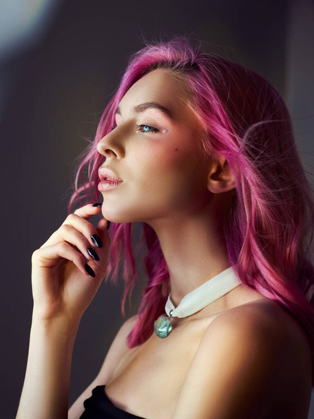 Beauty portrait woman with pink hair, creative vivid coloring. Bright colored highlights and shadows color on the face, a girl with jewelry. Dyed hair in the wind - Photo, image