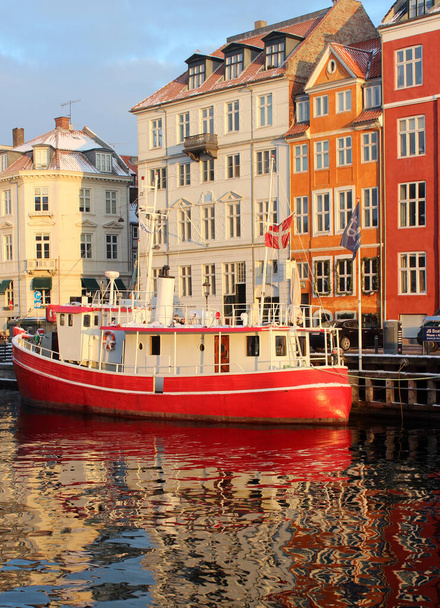 Słynny widok na ulice kanału kopenhaskiego. Słoneczny zimowy dzień w Kopenhadze. Błękitne niebo z chmurami. Klasyczna europejska architektura. Kolorowe ulice. łodzie na rzece. Piękne światło zachodu słońca.  - Zdjęcie, obraz