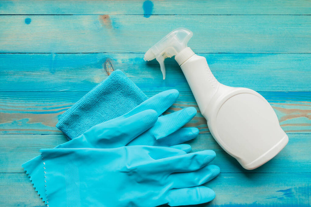 消毒用の掃除用品。消毒液、青ゴム手袋と青の木製の背景にマイクロファイバー布とホワイトスプレーボトル。衛生的な製品。パンデミックの予防と制御 - 写真・画像