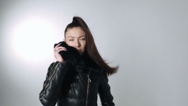 Mujer con el pelo largo en el viento en la chaqueta posando en el estudio sobre fondo blanco
 - Imágenes, Vídeo