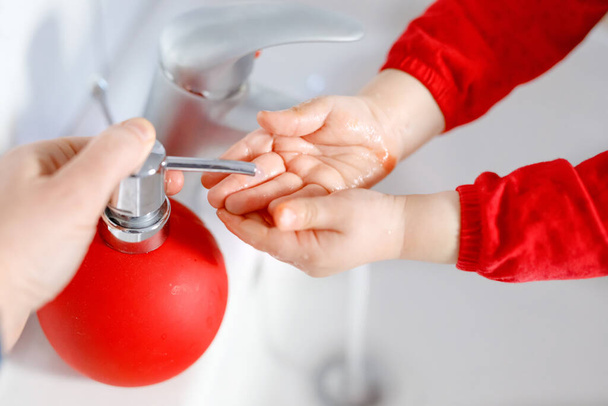 Egy kislányról, aki kezet mos szappannal és vízzel a fürdőszobában. Közelkép gyermek tanulás tisztító testrészek. Higiéniai rutineljárás vírusos megbetegedés esetén. gyerek otthon vagy óvoda. - Fotó, kép