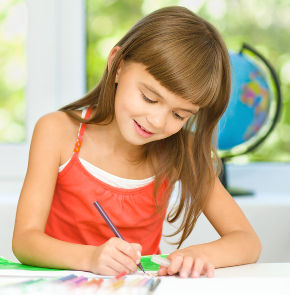 klein meisje is tekenen met behulp van potloden - Foto, afbeelding