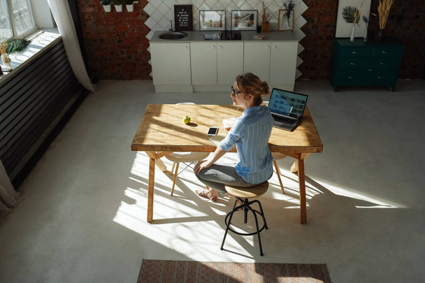 Top view woman working from home during quarantine. Sharp long shadows, bright sun. Home - 写真・画像