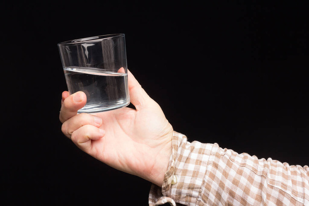 Прозора скляна чашка в руці людини. Скло наповнене водою або прозорою рідиною. Питна вода
 - Фото, зображення