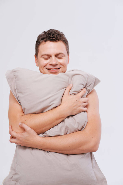 Studio portrait of sleepy man holding pillows  - Foto, imagen