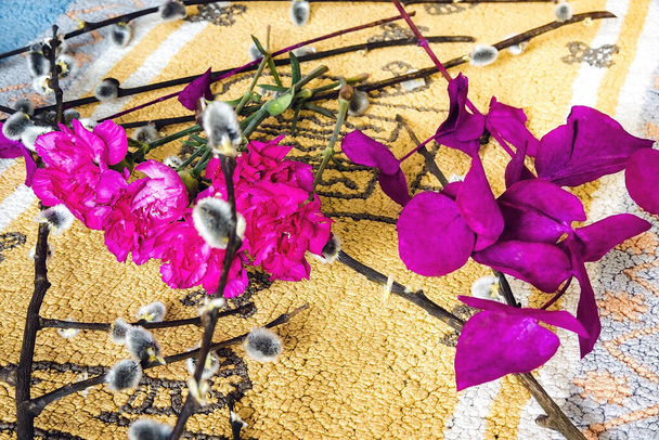 Na mesa festiva com raminhos de salgueiro, símbolo da Páscoa e flores vermelhas brilhantes
. - Foto, Imagem