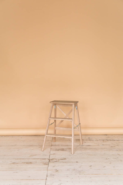 The working space of the photo studio with a beige paper background and chair. - Фото, изображение