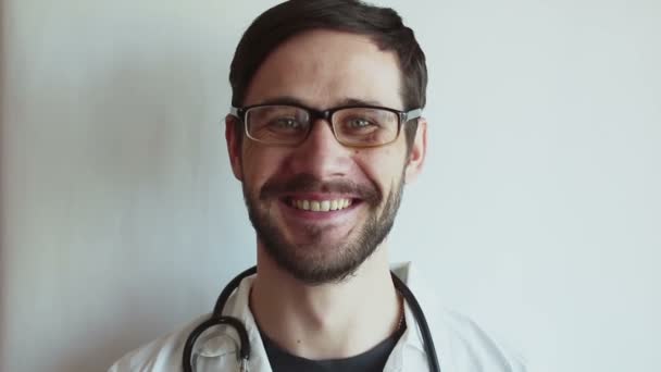 Young handsome doctor takes off his glasses and smiles broadly. A young doctor is pleased with the patient's recovery. - Séquence, vidéo