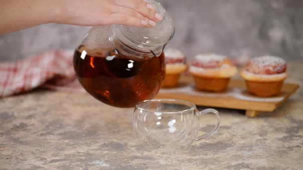 Kaada kuumaa teetä lasimukiin. Kuppi teetä ruusupullilla, makeita pullia sokerijauheella
. - Materiaali, video