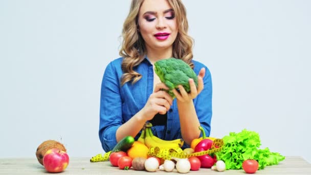 Mladá žena na přísné stravě na pozadí čerstvé zeleniny a ovoce - Záběry, video