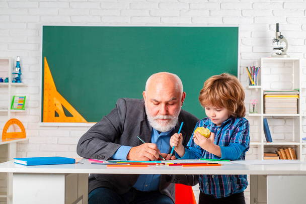 Professor and pupil in classroom at the elementary school. Child at school lesson with senior teacher. - Valokuva, kuva