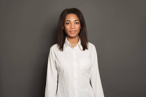 Siyah arka planda beyaz gömlekli akıllı Afro-Amerikan kadın, stüdyo resmi. - Fotoğraf, Görsel