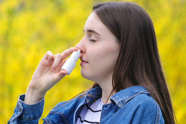  Polen alerjisi, parkta burun spreyi kullanan genç kız. - Fotoğraf, Görsel