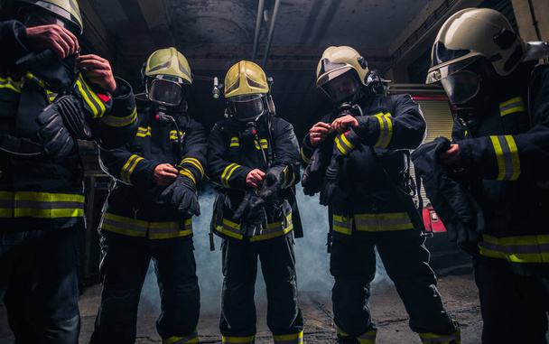 Tűzoltók csapata a tűzoltóságon gázálarcot és egyenruhát visel. - Fotó, kép