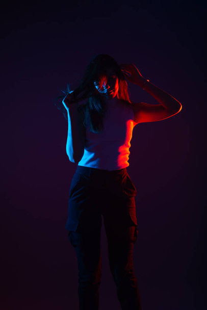 Siyah arka planda yüksek kontrastlı bir kadın modelin mavi ve kırmızı ışık portresi - Fotoğraf, Görsel