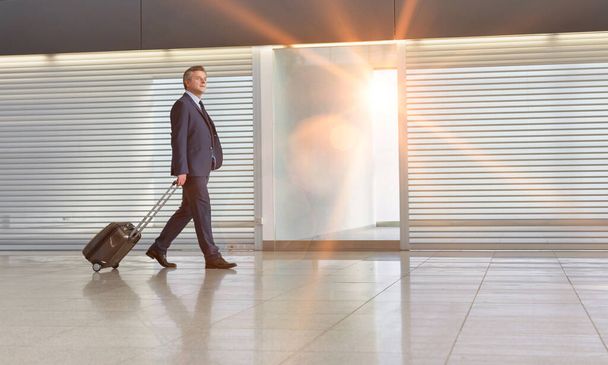 Mature businessman walking with his suitcase in the airport - Фото, изображение