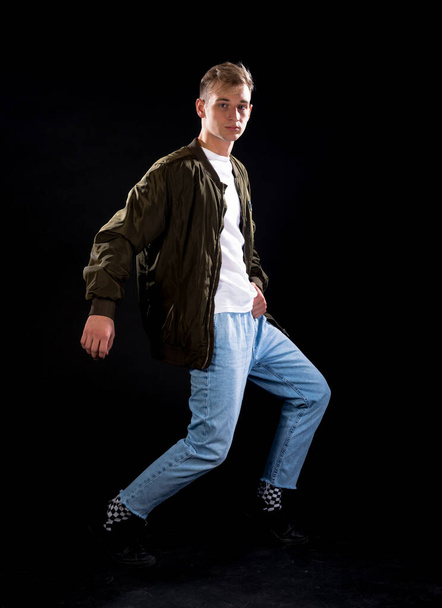 Studio body shot of a trendy young man wearing denim pants and green sport jacket - Foto, Bild