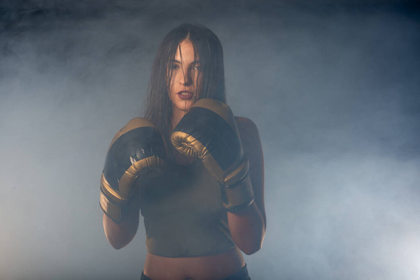 Mglisty obraz młodej i seksownej bokserki uderzającej bezpośrednim trafieniem rękawiczkami bokserskimi - Zdjęcie, obraz