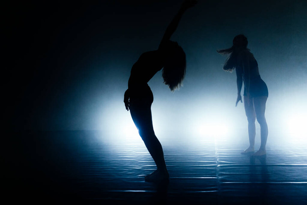 Caucasian silhouette females contemporary dancers exercising a dance routine - Fotografie, Obrázek