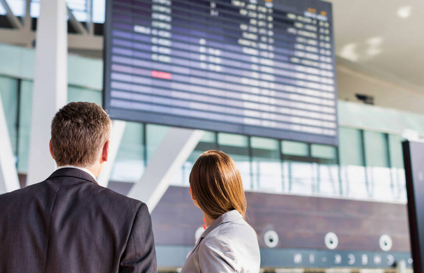 Business people looking on flight display screen in airport - Valokuva, kuva