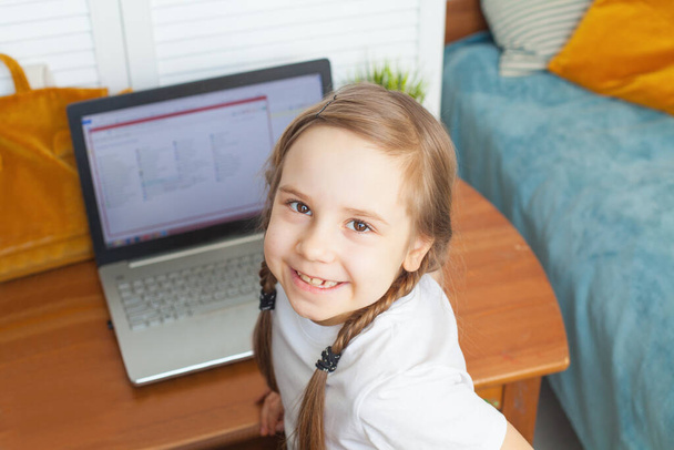 Чарівна дівчинка, яка вчиться вдома. Маленька дівчинка використовує ноутбук
 - Фото, зображення