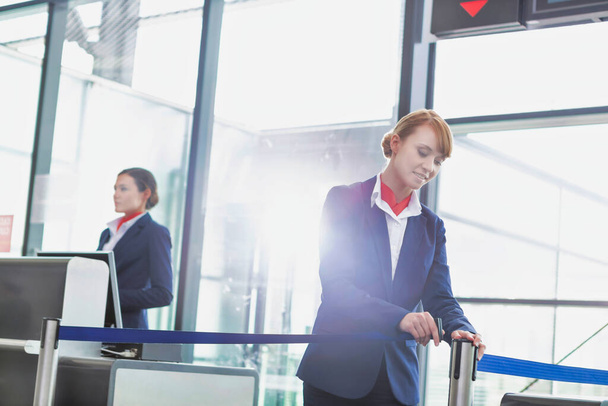 Portrait of young attractive passenger service agent opening the gate for boarding in airport - 写真・画像
