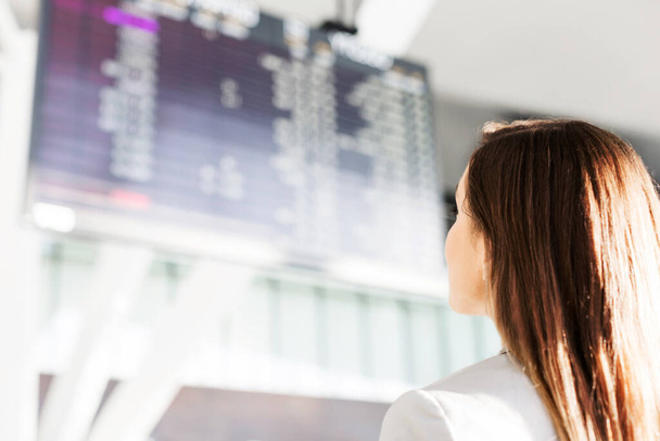 Businesswoman looking at flights display screen in airport - 写真・画像