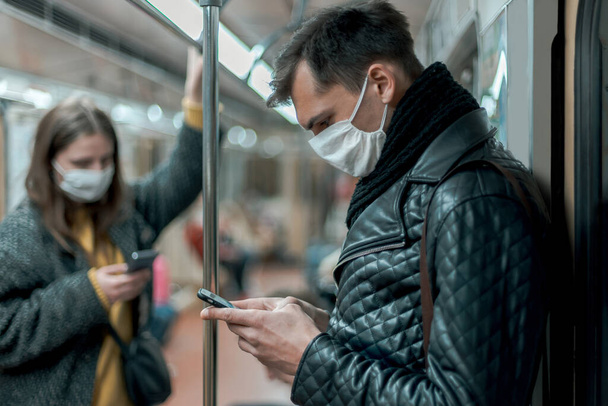 passengers in protective masks standing in the subway car. - 写真・画像