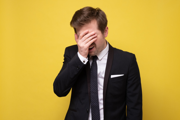 Handsome manin suit showing a facepalm being stressed ansd ashamed. Studio shot - Foto, afbeelding