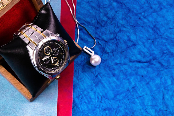 Primer plano de un reloj de pulsera de plata con collar de perlas borrosa sobre fondo azul. Año nuevo regalos concepto 2020
 - Foto, Imagen