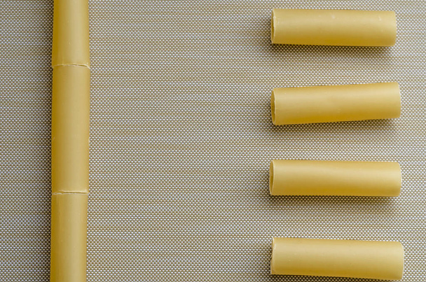 Een paar droge cannelloni buisjes. Ongebakken cannelloni op beige. Onvoorbereide pasta gevouwen in vormen en lijnen. Zicht van bovenaf. Selectieve focus. - Foto, afbeelding