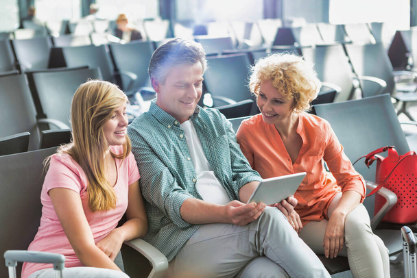 Mature man using digital tablet while his wife and daughter looking in airport - Fotoğraf, Görsel
