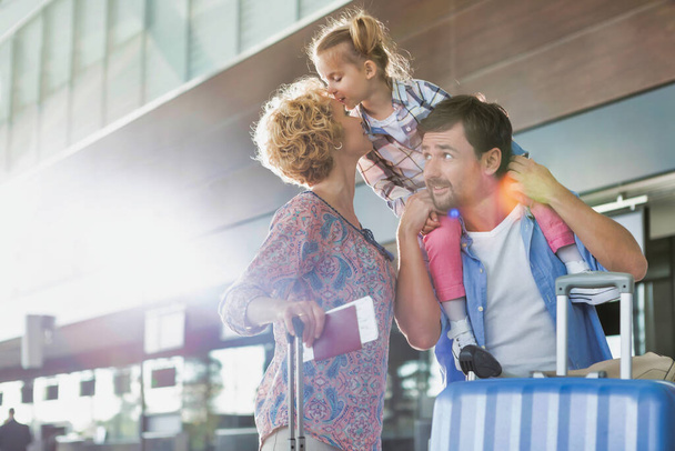 Πορτρέτο μιας χαρούμενης οικογένειας που φτάνει στο αεροδρόμιο με φωτοβολίδα φακού - Φωτογραφία, εικόνα