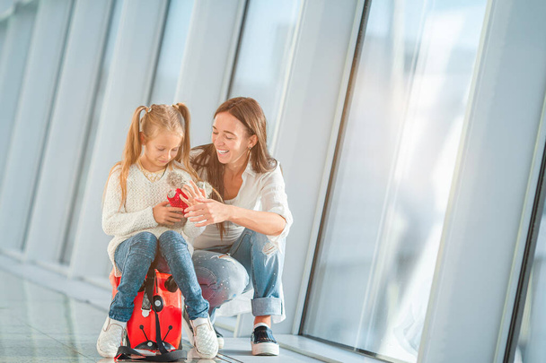 Gelukkige moeder en klein meisje met instapkaart op vliegveld - Foto, afbeelding